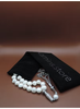 Pearl necklace with silver clasp on a black box labeled 'Kamins Store' against a brown background